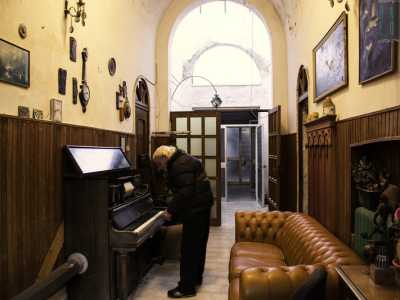 In un ampio corridoio con volta a botte scorgiamo quello che apparentemente sembra un comune e antico pianoforte a muro ma che al contrario suona da solo